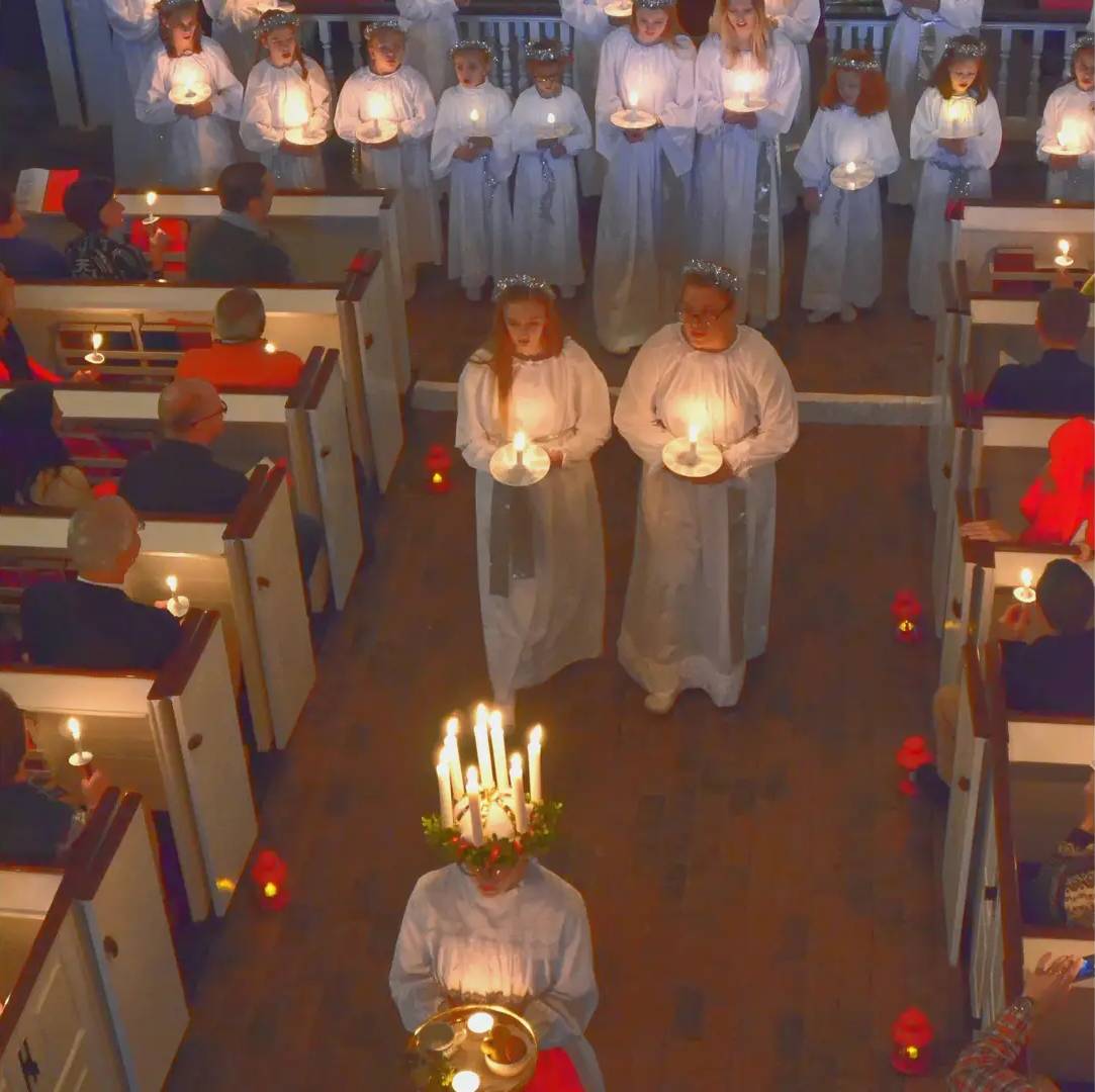 A group of people praying in the church holding candles.